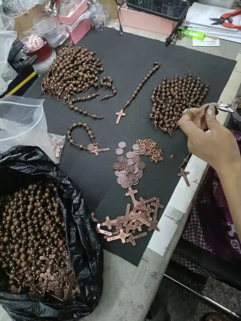 Table with rosaries and religious accessories on a workshop table.